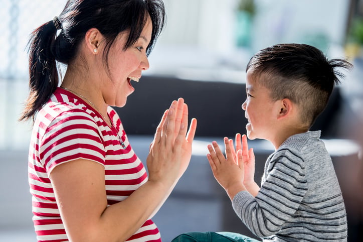 child with autism clapping and repeating pattern with his mother