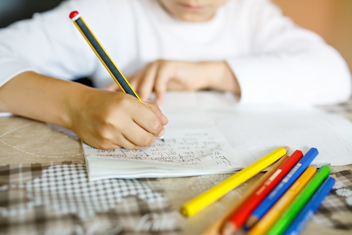 child with autism practicing writing words with different colored pencils