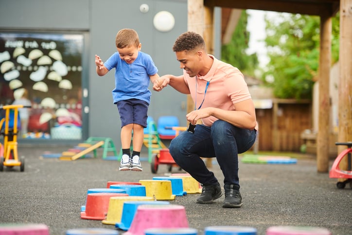 Daycare teacher with child with autism in playground