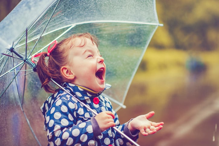 girl with autism playing in the rain with umbrella