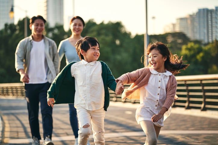 Asian family with two children taking a walk in city park