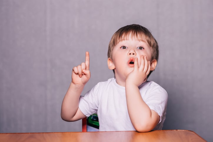 Little boy with autism sitting on chair at the table wanting to speak