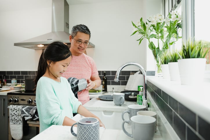 little girl with autism in the kitchen washing dishes with her father