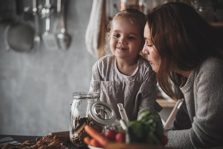mother and daughter with autism standing over kitchen counter and eating cookies together, learning intraverbals