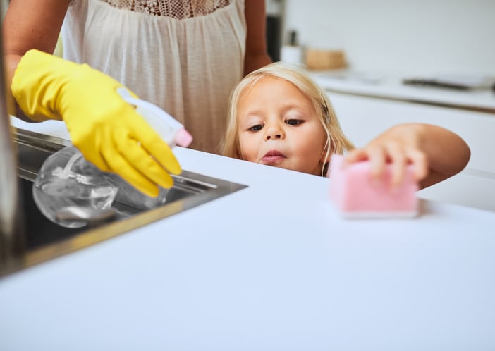 mother and her little daughter with autism cleaning a kitchen surface together at home