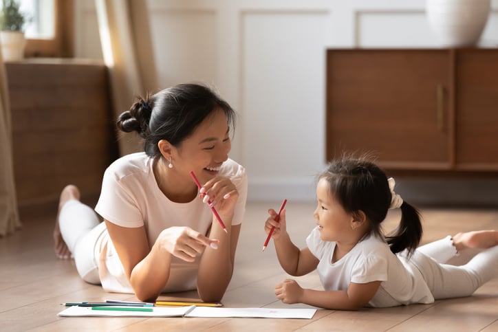 mother and her small daughter with autism lying on warm wooden floor in sunny cozy living room, learning intraverbals