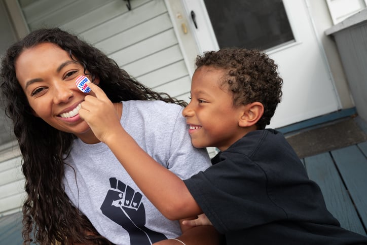 son-placing-i-voted-sticker-on-mothers-cheek