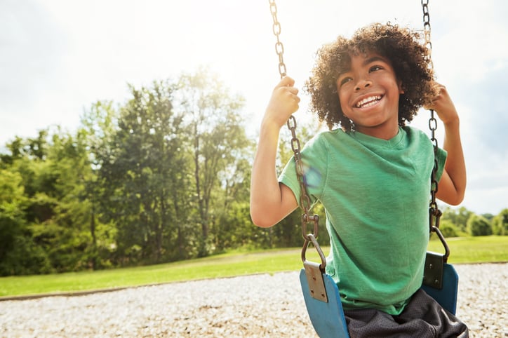 young boy with autism playing on a swing at the park