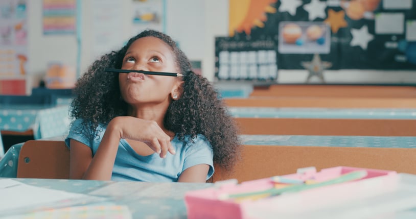 young girl with autism looking bored while playing at a school desk