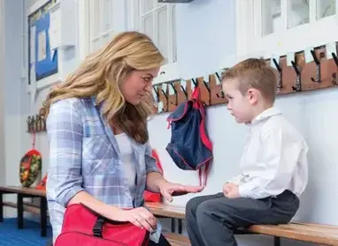 Teacher sitting at eye level with elementary student, both holding picture cards during one-on-one instruction
